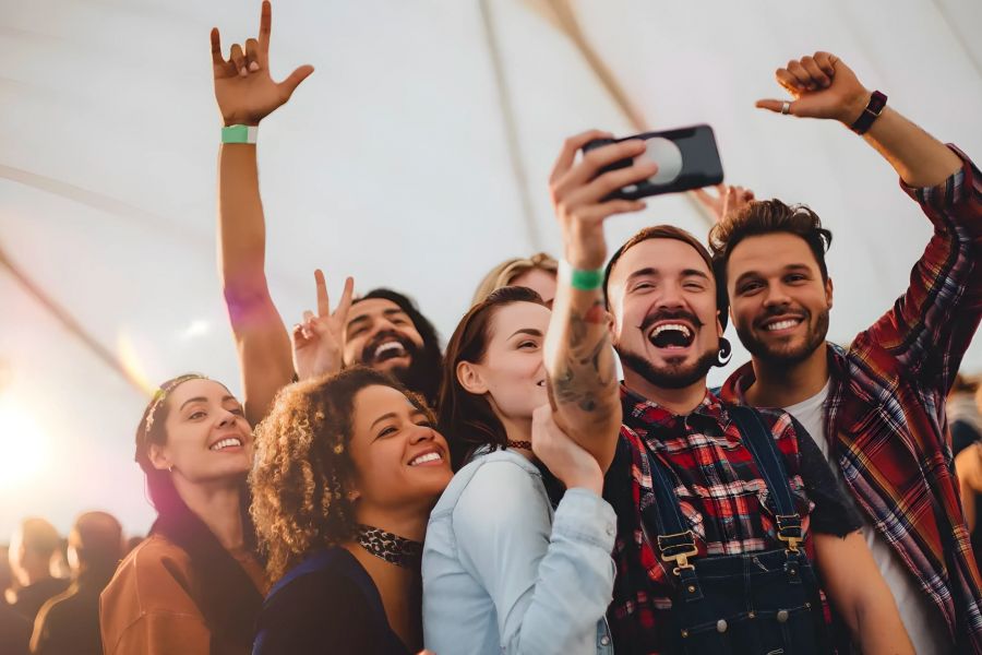 Solace Apartments A group of friends smiling and taking a selfie together at an outdoor event with sunlight in the background.
