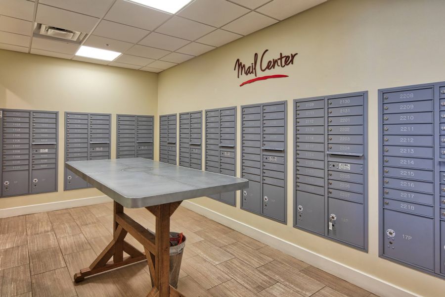 Solace Apartments A mail center room with gray mailboxes on the walls and a table in the middle.