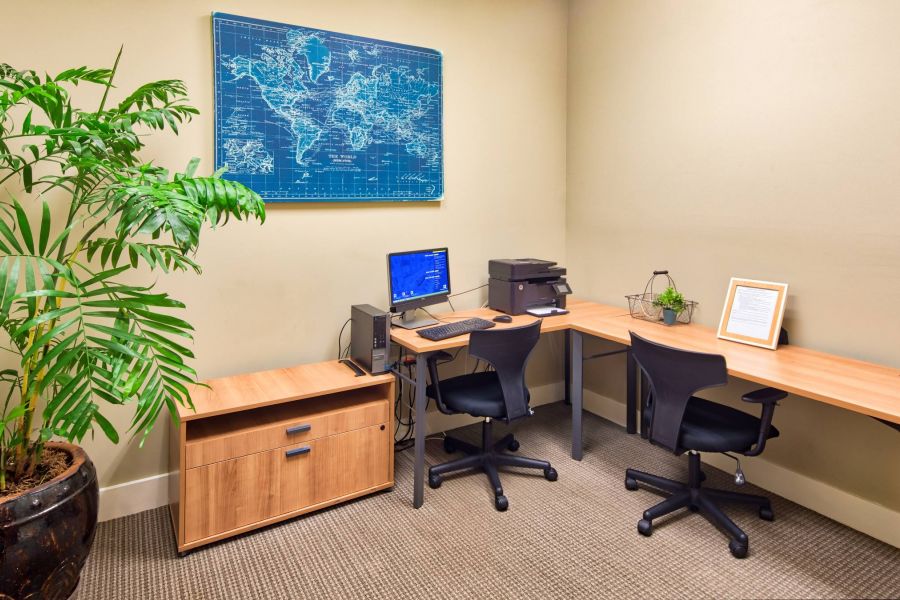 Solace Apartments Small modern office with two desks, chairs, a computer, printer, plant, and a world map on the wall.